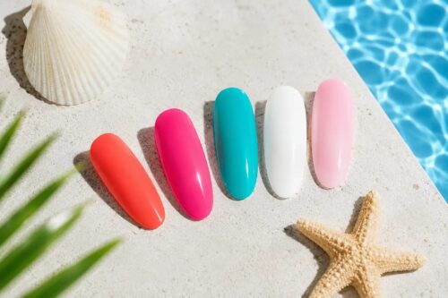 Tip per unghie nei colori corallo, fucsia, turchese, bianco e rosa baby su sfondo ispirato al mare, protagonisti delle tendenze unghie estate 2026.