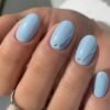 Manicure estiva con smalto azzurro e decorazioni minimal in argento su unghie ovali, elegante e raffinata.